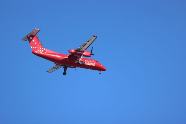 red plane of air greenland flying in a blue sky